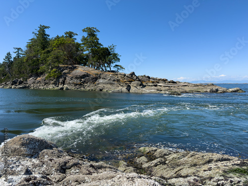 A chaotic funnel of white-water rapids, standing waves, and swirling whirlpools in a narrow gap between islands in British Columbia