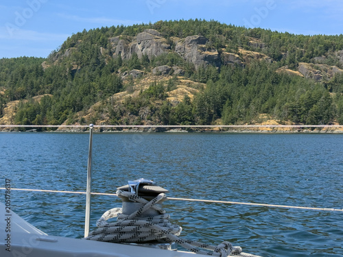 View from a sailboat cruising past steep, tree-covered cliffs