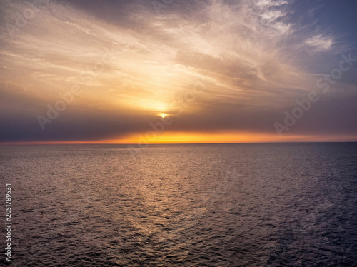 Rayon de lumière dorée transperçant des nuages spectaculaires au coucher de soleil sur mer infinie