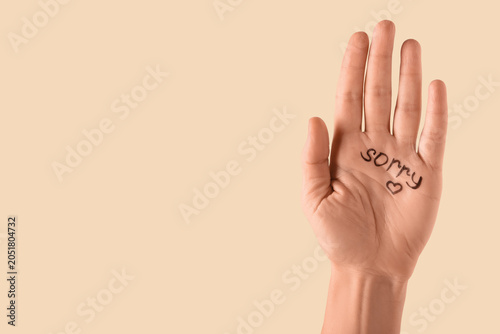 Quadro su tela Female hand with written word SORRY on beige background