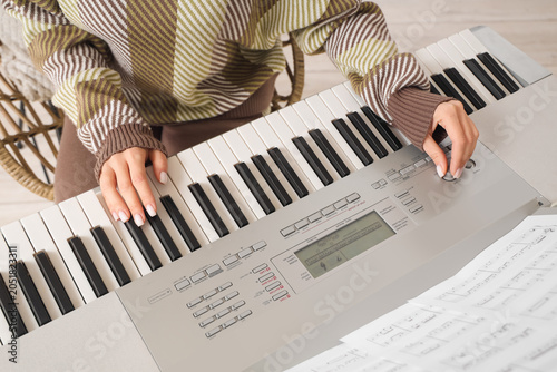 Young woman playing synthesizer at home, closeup