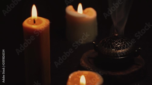 Three magic Christmas wax candle flames calm burning in home in white smoke from incense aroma stick on black dark background with copy space. Closeup yoga, spa, wellness, relaxation. No people