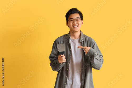 Fotografie Young Asian man pointing at putty knife on yellow background