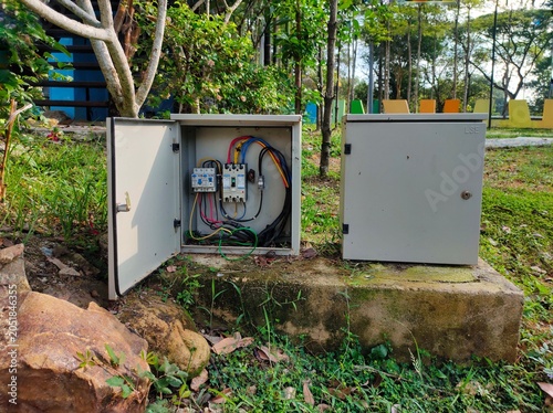 Slika na platnu Two electrical boxes, one of which is open, show that the wires in the playground are very dangerous to visitors, especially children