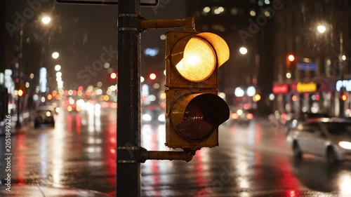 Red traffic light on a rainy city street at night with blurred lights and wet asphalt