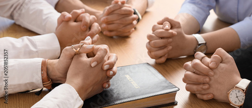 Schilderij op canvas Group of people praying with Holy Bible at table in office, closeup