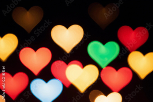 Colorful hearts glow softly against a dark background.