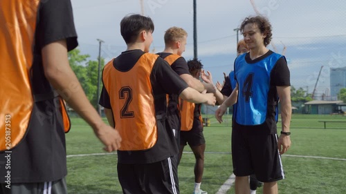 Two teams of diverse football players touching hands before soccer match. 