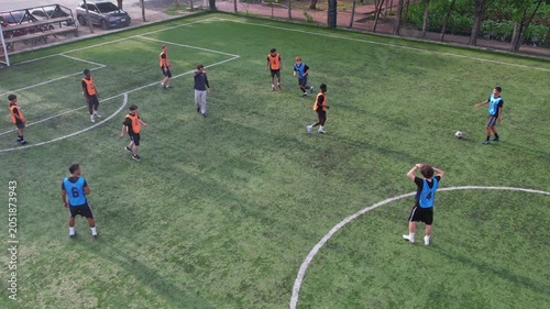 Aerial view of football players practicing with coach on outdoor field. 