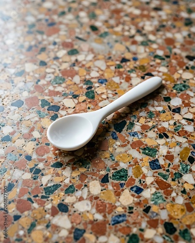 white ceramic spoon on colorful terrazzo stone surface