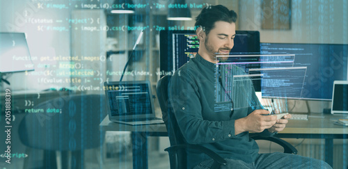 Male programmer with phone at workplace in office