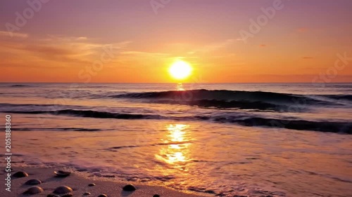 Sunset at the beach with gentle waves rolling on the sand near the ocean