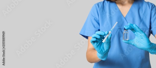 Fotografía Medical professional in blue scrubs and gloves holding syringe and vial for vacc