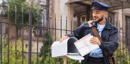 Foto Smiling mailman delivering letters to mailbox, postal service and communication,