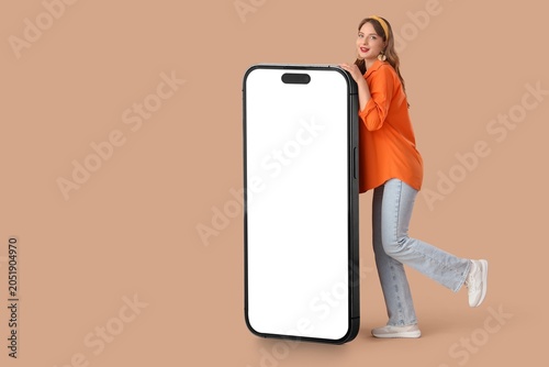 Obraz na plátně Young woman leaning on giant smartphone with blank white screen, mobile app prom