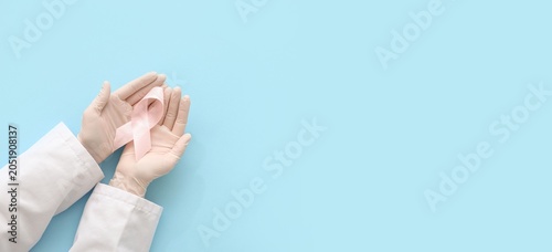 Fotografie Breast cancer awareness pink ribbon in doctor's hands, medical support and healt