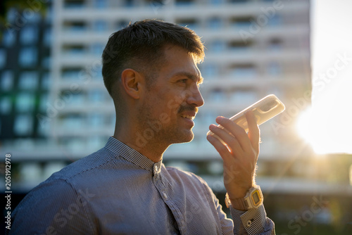 Tableau sur toile Man using smartphone voice assistant in urban setting