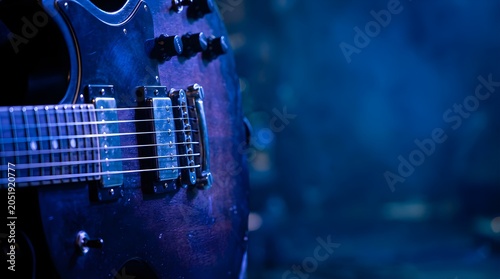 Electric guitar close up on stage with blue atmospheric concert lighting
