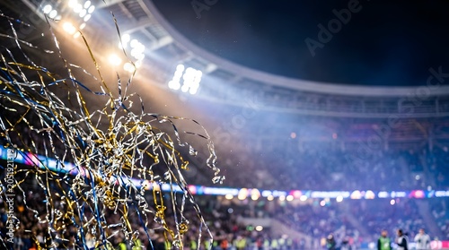 Gold and blue confetti falling at a night sports stadium celebration