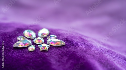 Sparkling crystal gems arranged like a flower on purple velvet fabric
