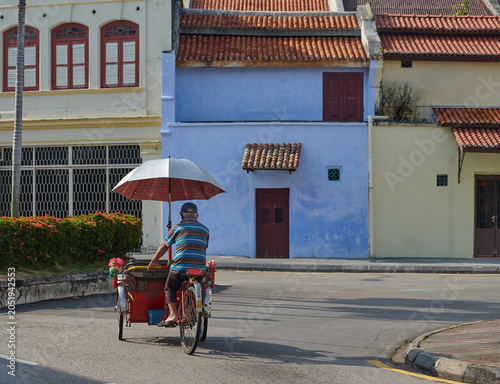 Obraz na plátně Traditional trishaw rider cycling past Nanyang heritage houses in George Town, P