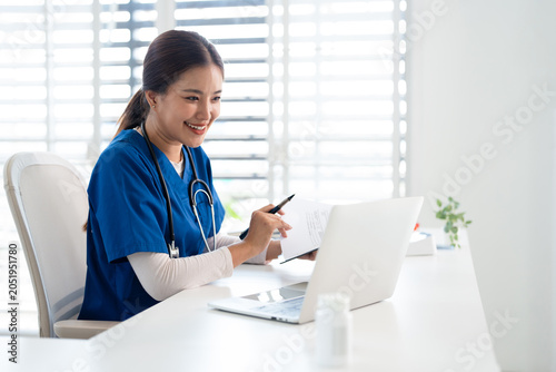  professional  doctor using laptop computer in hospital office watching medical webinar training, writing in healthcare report,