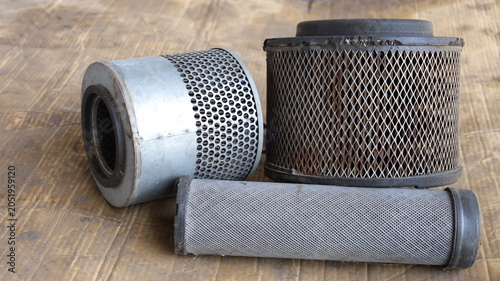 Used car air filter. Close-up of pile of old car air filters of different styles and sizes on dirty cardboard background with selective focus.