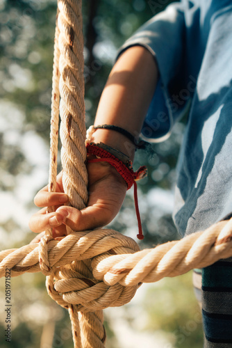Close-up of a child’s hand gripping a rope climbing structure in an outdoor playground. Concept of adventure, balance, motor skill development, confidence, and active childhood.