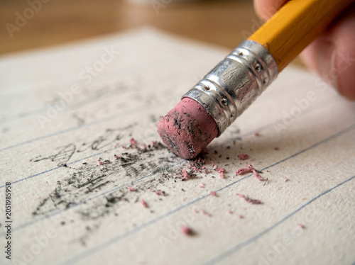Macro view of pencil pink eraser erasing graphite text on paper