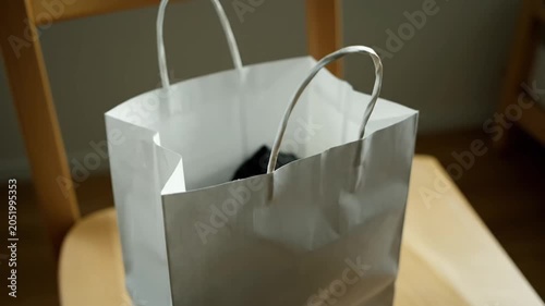 Silver Paper Shopping Bag Resting on a Wooden Chair Indoors.