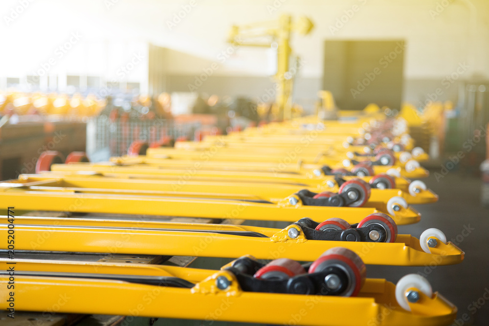 Fototapeta premium Row of yellow forklift forks with wheels in factory