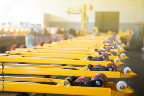 Row of yellow forklift forks with wheels in factory
