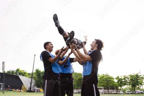 Foto Low angle view of soccer players lifting teammate celebrating victory
