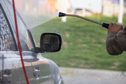 Car washing with a high pressure water jet at an outdoor self-service  car wash station.