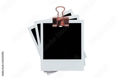 A stack of three empty white instant frames held together by a single rose gold metal binder clip isolated on a black background