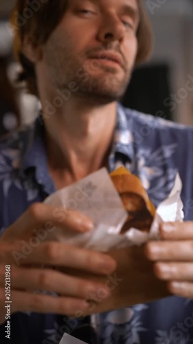 Man in floral shirt happily enjoying a sandwich