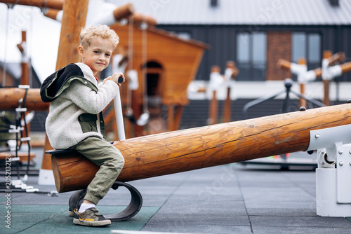 Billede på lærred Blond preschooler boy enjoying his time on a wooden seesaw in a modern playgroun