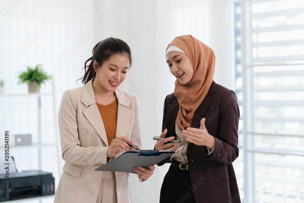 Obraz premium Two business colleagues multiethnic working in office, asian muslim