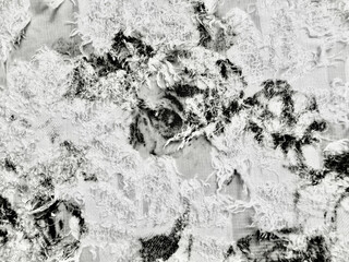macro textured shot of distressed organic linen fabric with abstract black tie dye patterns and frayed fibers