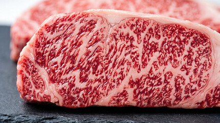 Extreme macro photography highlighting incredible fat marbling texture within premium raw wagyu beef steak resting on dark slate board for luxury culinary preparation