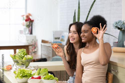 Obraz na płótnie Kitchen Fun:Friends Enjoy Making Salad:This vibrant image captures two friends having a joyful time in the kitchen