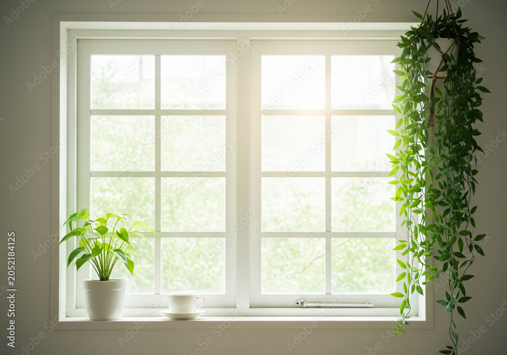 Fototapeta premium White coffee cup and saucer sit on bright sunny window sill with lush green trees outdoors creating a sense of peace.