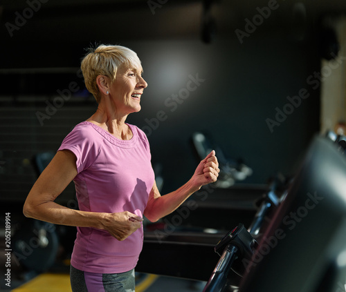 Portrait of a senior elderly woman exercising in a gym, running using threadmill machine equipment, healthy lifestyle and cardio exercise at fitness club concepts, vitality and active senior