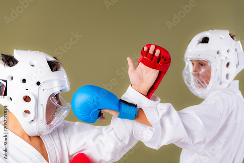 Photos Karate athletes simultaneously throw punches at each other's head level in a close range exchange, with both red and blue gloves making near contact during a fast paced competitive sparring drill