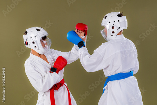 Photography Two young karate competitors trade simultaneous punches at close range during an intense sparring drill, both maintaining upright stances while engaging in rapid upper body striking exchange