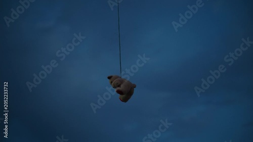 Stuffed bear toy suspended high in the air with large copy space. Surreal image representing isolation, vulnerability, memories and mental health themes. 4K.