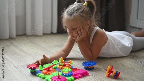 Child engaged in assembling bright plastic gears into structure, sitting on floor. toy fosters coordination, cognitive skills, and creative thinking, ideal for childhood development activities.