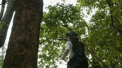 Young woman hiking uphill on a steep trail in a lush green forest, exploring nature on an adventurous journey