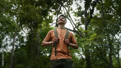 Young adventurer with backpack enjoying the tranquility of nature standing in the middle of a lush green forest