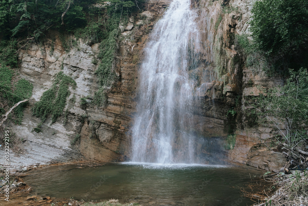 Fototapeta premium Majestic waterfall cascading into a rocky pool.